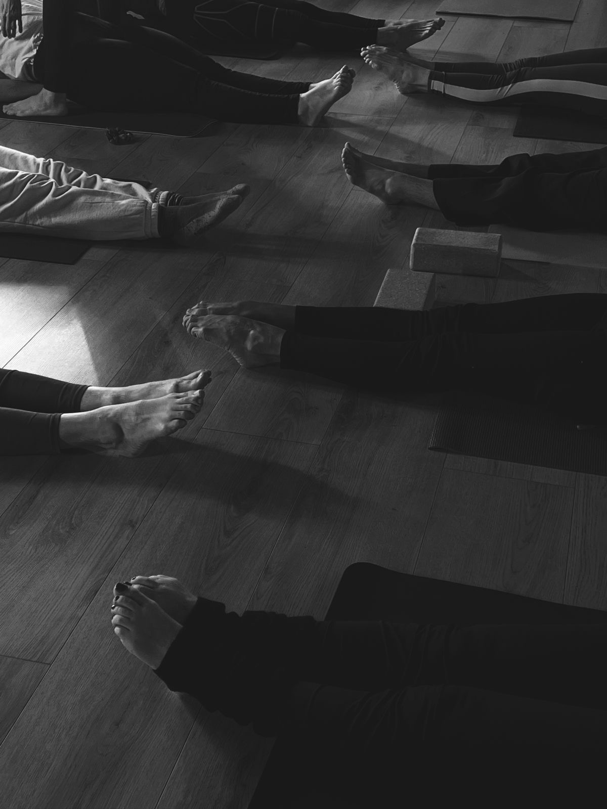 Black and white photograph of a class resting on the studio floor, feet in view