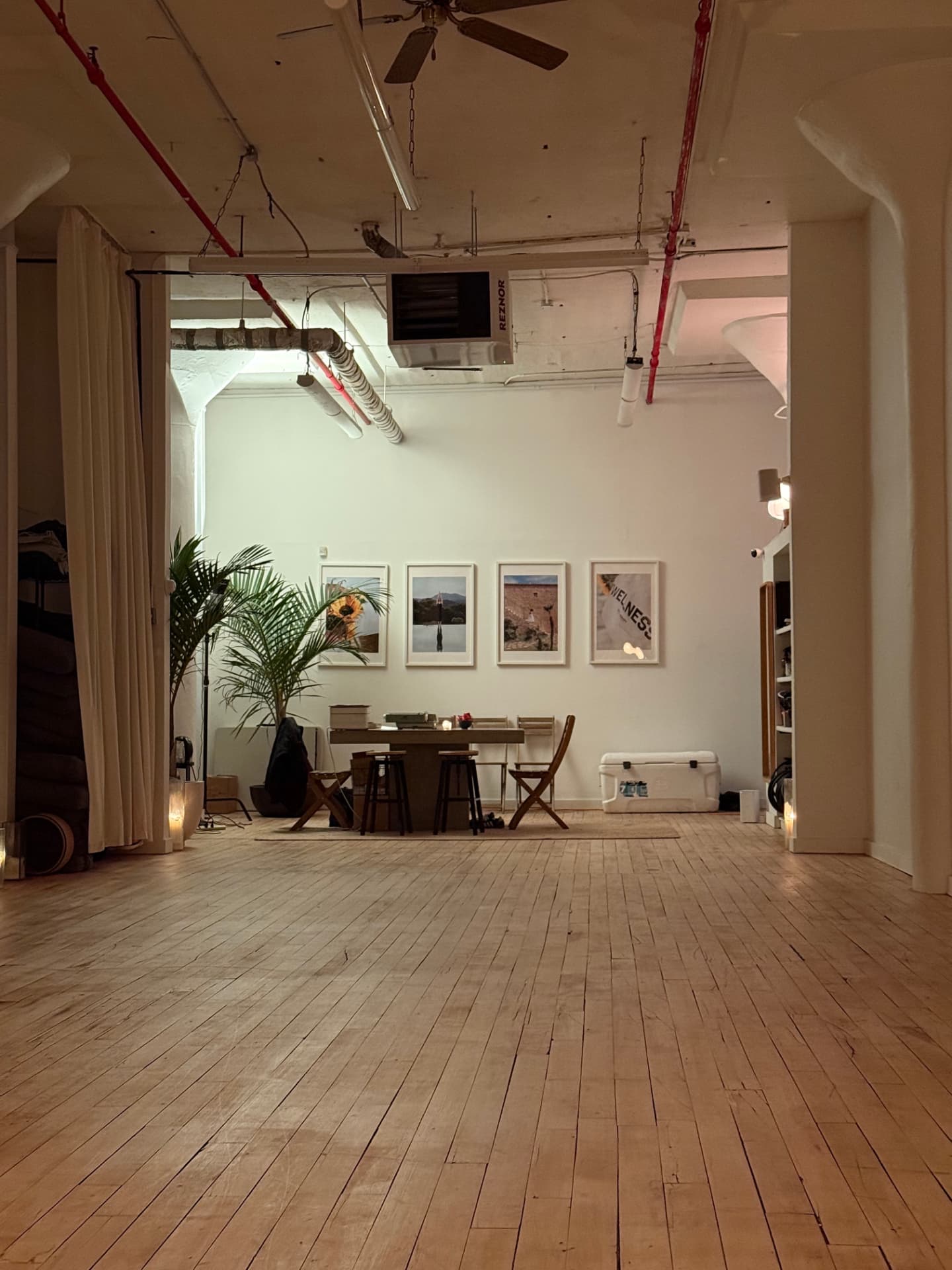 The open studio floor with framed prints, plants, and a long wooden table