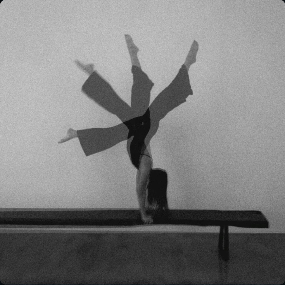 Black and white long exposure of a person inverted in movement on a studio bench